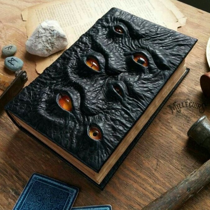 Um livro com capa de couro preto e olhos amarelos sobressalentes.